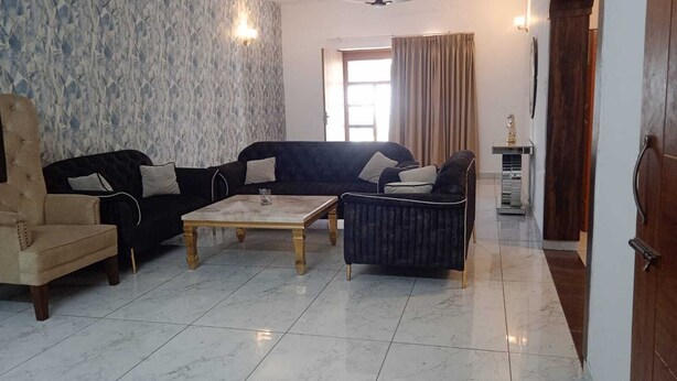 A living room with a sofa, armchair, and coffee table. - Fursat Villa (Mohali)
