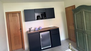 A compact kitchenette with a built-in coffee maker, a small refrigerator, and a wooden countertop. - Apartment 1 im EG mit Kitchenette (Prerow)
