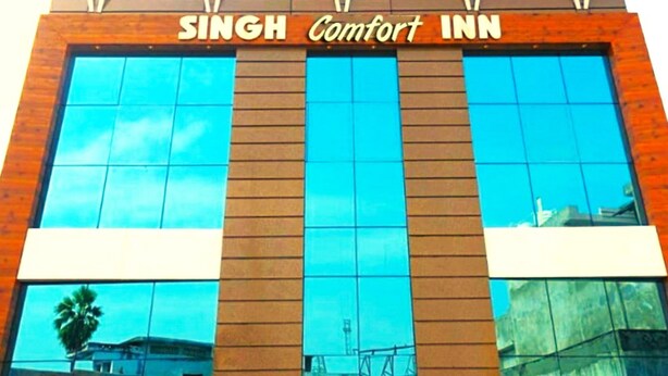 L'esterno del Singh Comfort Inn, dal design moderno, con ampie vetrate e un cartello ben visibile.