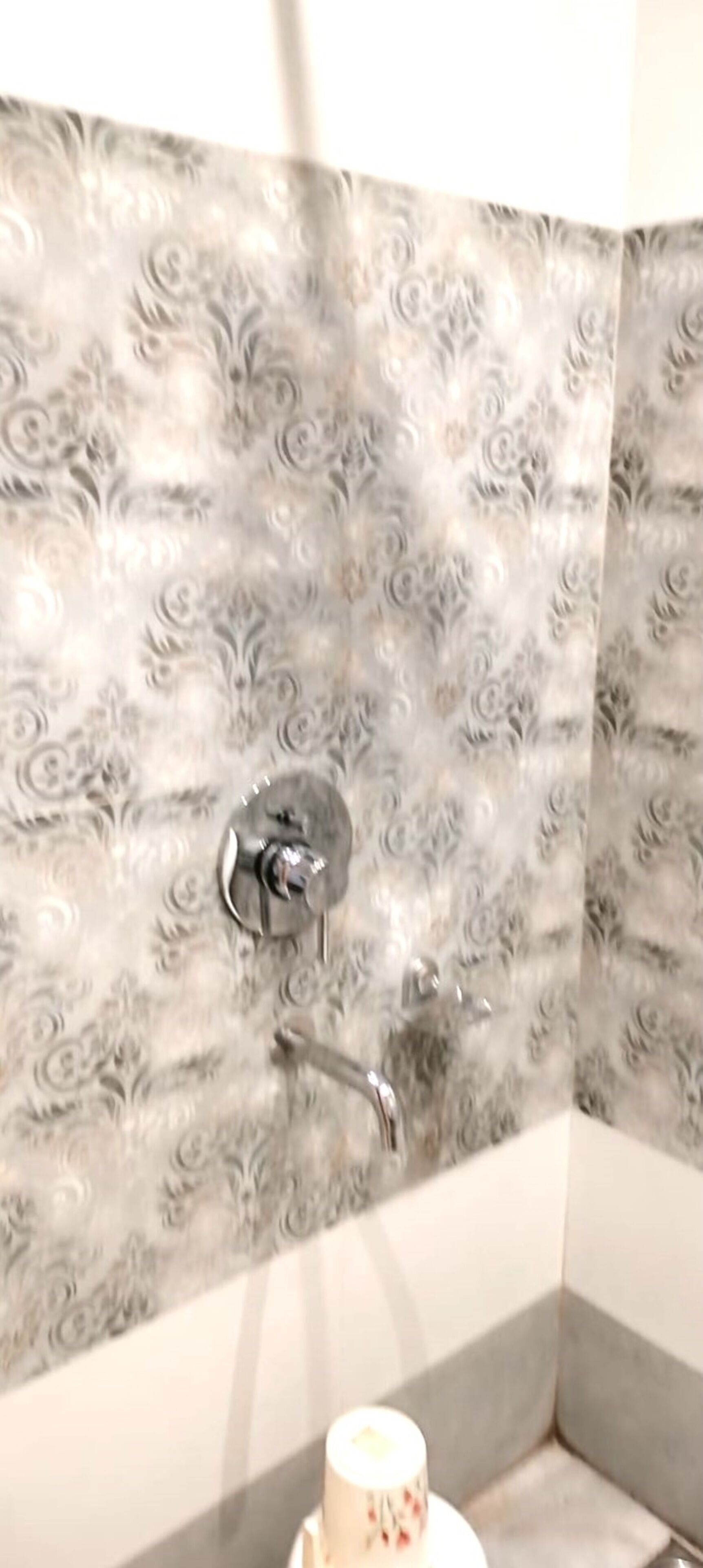 A bathroom with patterned tiles, a showerhead, and a toilet.