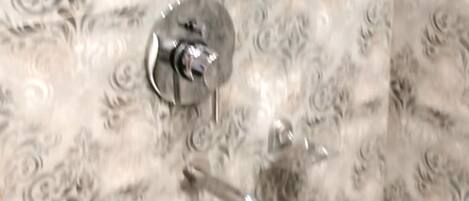 A bathroom with patterned tiles, a showerhead, and a toilet.