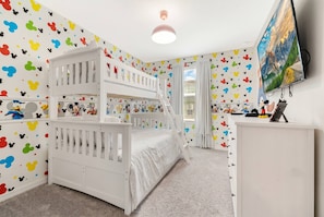 A child's room with bunk beds, a desk, and a TV.