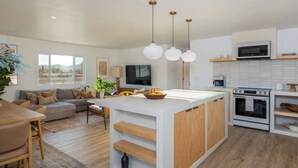 Une cuisine moderne dotée d’un îlot central, de meubles blancs et d’un four à micro-ondes placé au-dessus de la cuisinière.