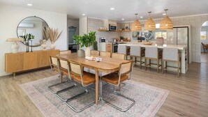 Une cuisine moderne dotée d’un îlot central, de luminaires suspendus et d’un coin repas avec une table ronde et des chaises.