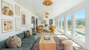 Un salon spacieux avec un canapé vert, une table basse en bois et des fauteuils en osier.
