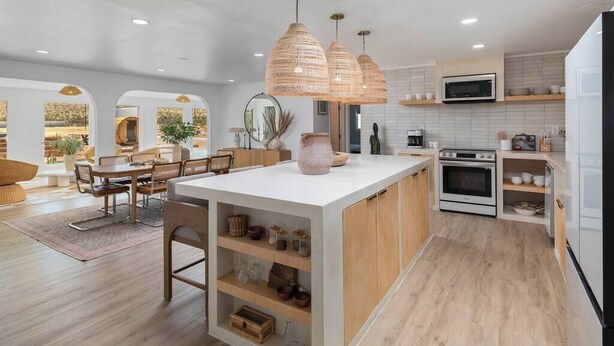 Une cuisine moderne dotée d’un îlot central, de luminaires suspendus et d’un coin repas offrant une vue agréable.