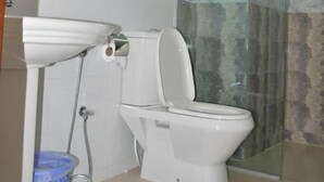 Un baño con inodoro, lavamanos, cabina de ducha de vidrio y toallero.