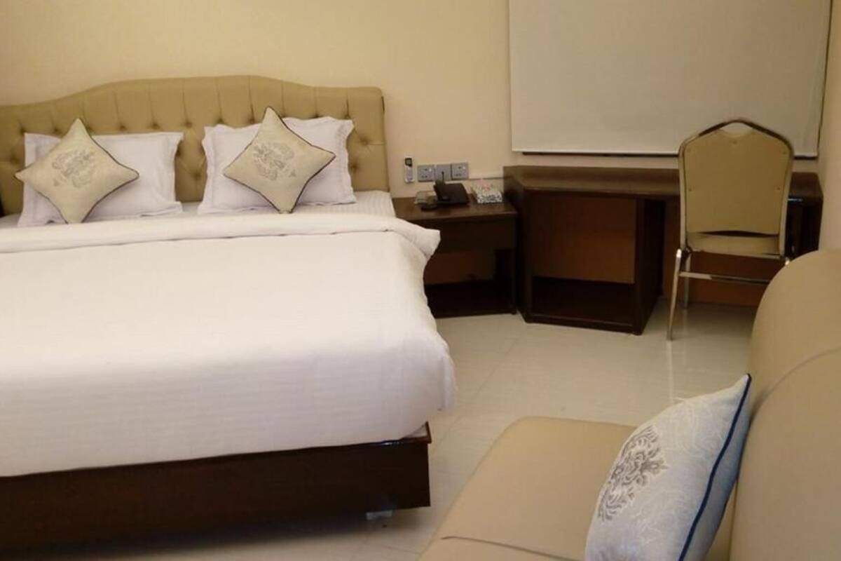 Una habitación de hotel con cama, escritorio, silla y sofá.