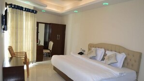 Habitación de hotel con una cama grande, un escritorio y una silla. Hay un armario y un espejo en la habitación.