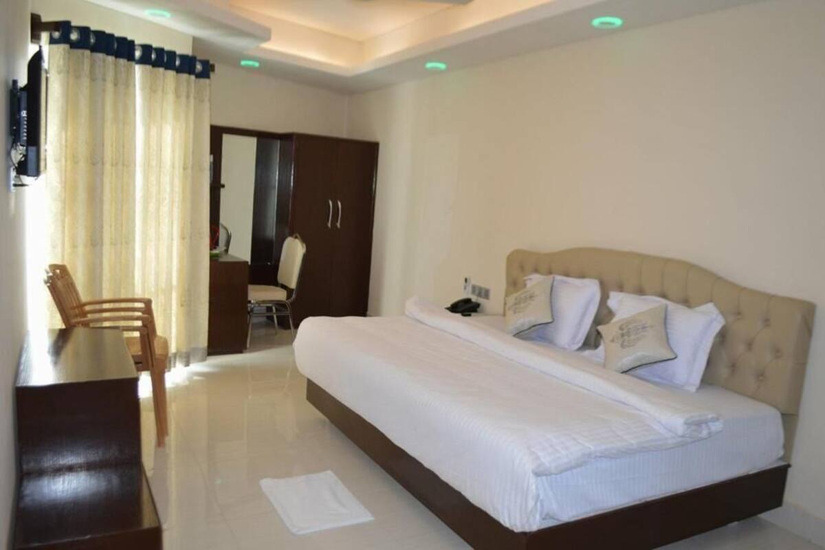 Habitación de hotel con una cama grande, un escritorio y una silla. Hay un armario y un espejo en la habitación.