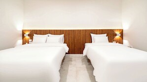 A hotel room with two beds, wooden headboard, white bedding, and wall-mounted lights. - hotel77 (Chuncheon)