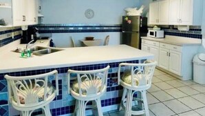 A kitchen with a central island, white cabinets, and blue-tiled backsplash.