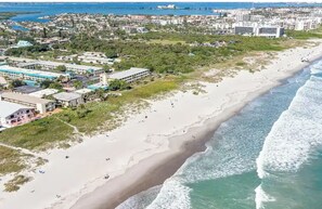 Vue aérienne d’une plage, avec des bâtiments et de la végétation à proximité.