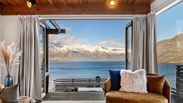 Ein Zimmer mit einem großen Fenster, das Blick auf einen See und Berge bietet.