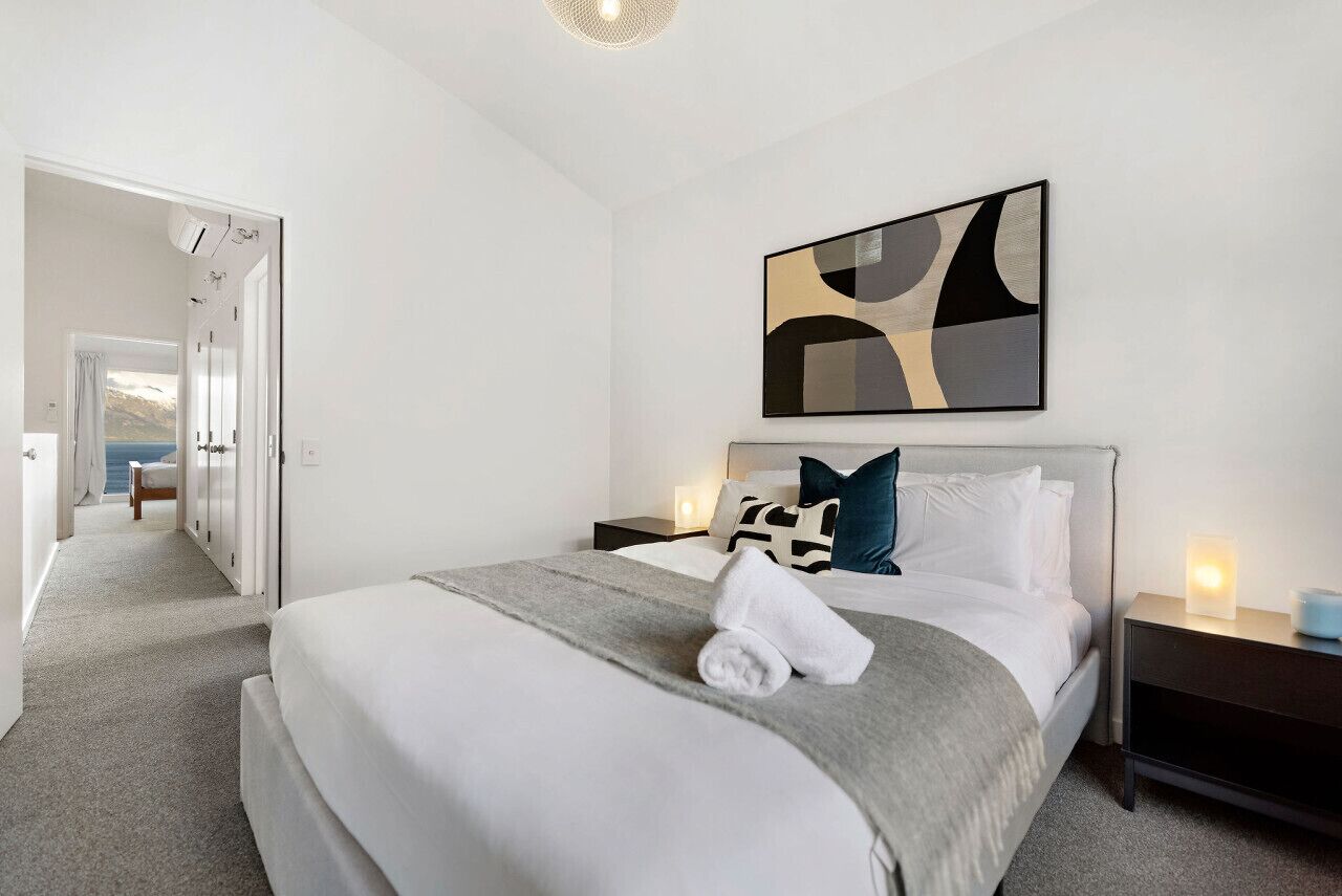 Una habitació d'hotel moderna amb un llit gran, una tauleta de nit amb una làmpada i un quadre a la paret.
