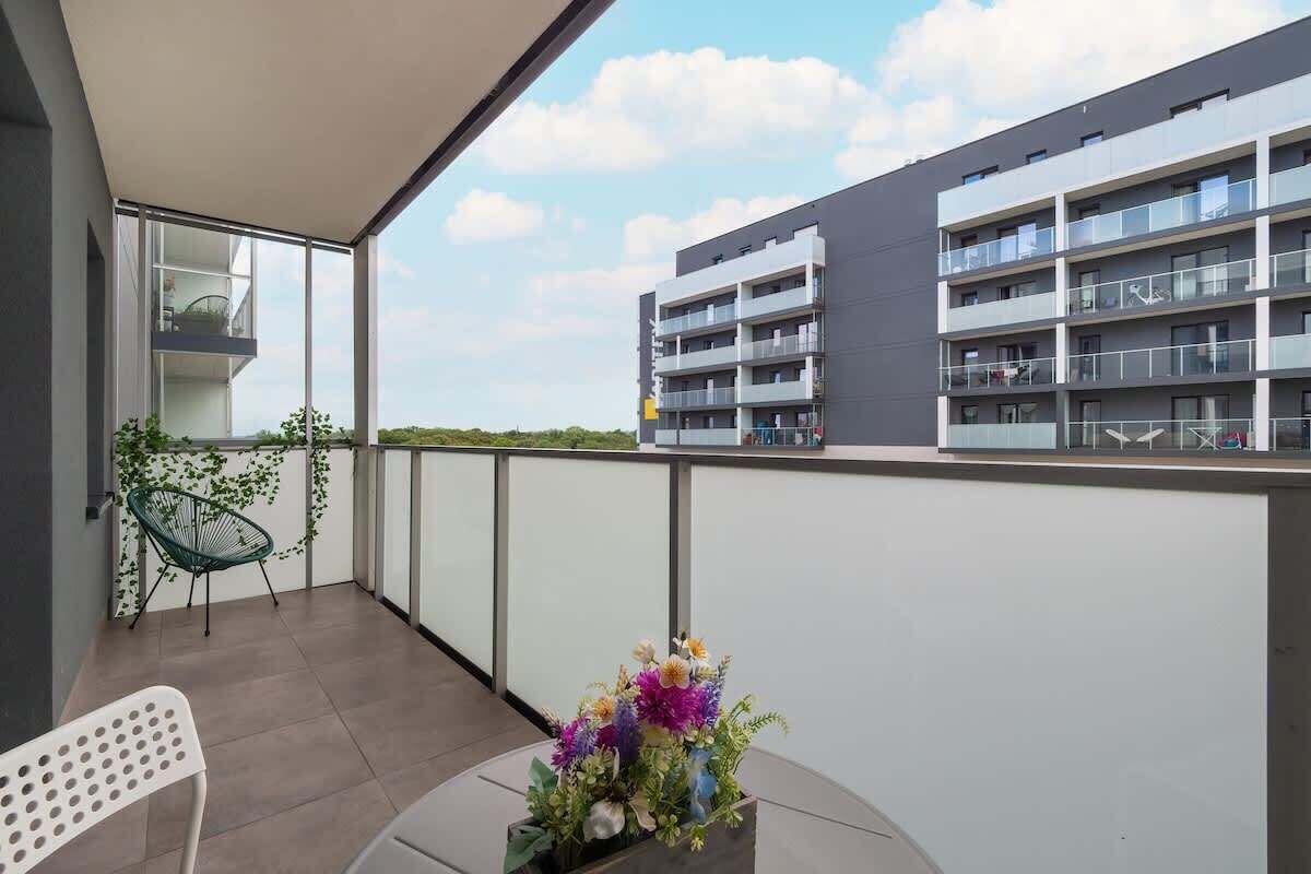 A balcony with a chair, a table, and a flower arrangement.