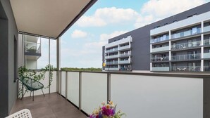 A balcony with a chair, a table, and a flower arrangement.