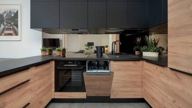 A modern kitchen with wooden cabinets, a dishwasher, and a black countertop.