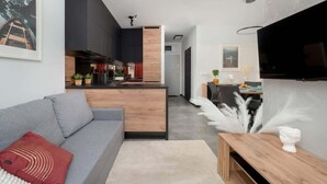 A modern living room with a grey sofa, wooden coffee table, and a TV mounted on the wall.
