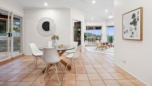 Een moderne eethoek met een ronde tafel, witte stoelen en een decoratieve spiegel.