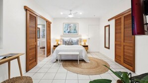 Een slaapkamer met een bed, nachtkastjes, een plafondventilator en een grote spiegel.