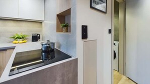A modern kitchen with a built-in stove, a small plant, and a coffee maker. - Functional Studio with Balcony | Close to Green Areas (Warszawa)