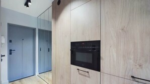 A modern kitchen with a built-in oven and a mirrored wall. - Functional Studio with Balcony | Close to Green Areas (Warszawa)