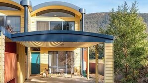 A modern house with a covered patio, large windows, and a view of a mountainous landscape. - Clematis Hideaway (Halls Gap)