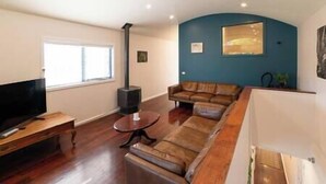 A living room with a sofa, a TV, and a fireplace. - Clematis Hideaway (Halls Gap)