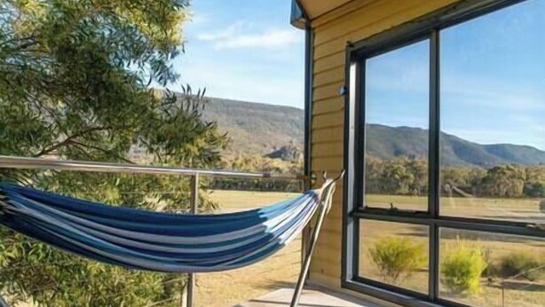 A hammock on a balcony with a view of a mountainous landscape. - Clematis Hideaway (Halls Gap)