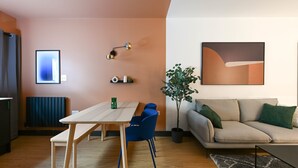 Un salon moderne avec une table à manger en bois, des chaises bleues, un canapé beige et une plante en pot.