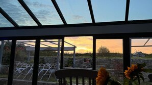 Um solário com vista para o pôr do sol, uma cadeira e um girassol.