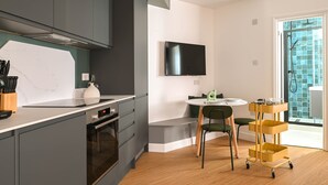 Una cucina moderna con mobili grigi, forno integrato e zona pranzo con tavolo e sedie rotonde.