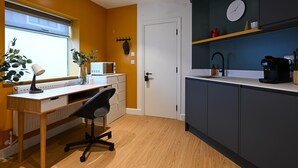 Una cucina moderna con una scrivania in legno, una sedia, un forno a microonde e una macchina per il caffè.