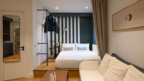 Una camera d'albergo moderna con un grande letto, un divano, un tavolino in legno e uno specchio.