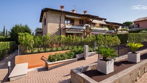 Un immeuble à plusieurs étages doté de balcons, d’une cour pavée et de plantes en pot.