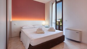 Une chambre moderne avec un grand lit, une table de chevet, une lampe de chevet et une vue sur l’extérieur.