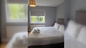 A bedroom with a bed, a window, a radiator, and a lamp. - Large 3BD Duplex, 20Min to Airport (Dublin)