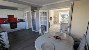 A modern kitchen with white cabinets, a red backsplash, and a dining area with a round table and woven placemats. - Bright 2BD Family Home with Hidden Zen Den & Garden (Dublin)