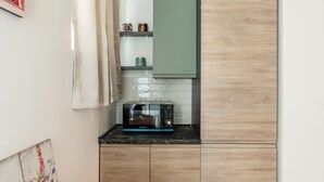 Eine kleine Küche mit einer Mikrowelle, einer kleinen Ablage mit Gläsern und einem grünen Schrank.