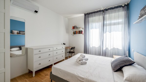 Un dormitorio con cama, cómoda, escritorio y estantería.