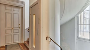 Un couloir doté d’un plancher en bois, d’une porte blanche et d’un escalier muni d’une rampe en métal.