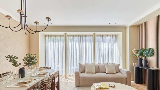 Un salon moderne comprenant un canapé, une table basse et un coin repas avec des chaises et un lustre.