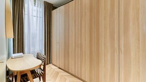 Une chambre moderne avec une armoire en bois, une petite table accompagnée d ’une chaise et un parquet à motifs en chevrons.