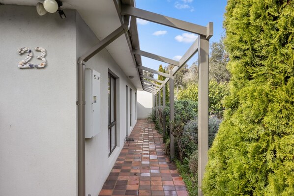 A narrow corridor with a tiled floor, a white exterior wall, and a number '23' sign. - Between Beaches - Family/Pet friendly (Rye)