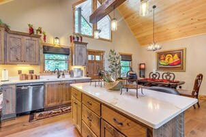 Una cocina amplia con armarios de madera, una isla grande y un comedor con candelabro.