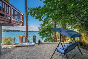 Eine Terrasse mit Seeblick, einem Schaukelstuhl und einem kleinen Tisch.