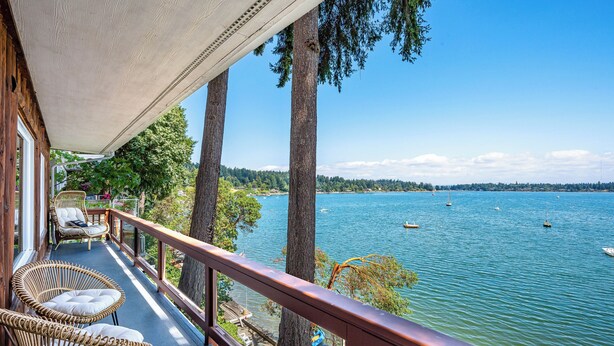 A balcony with wicker chairs and a view of a lake with boats. - Waterfront Vashon Island Home, Beach Access & View (Vashon Island)