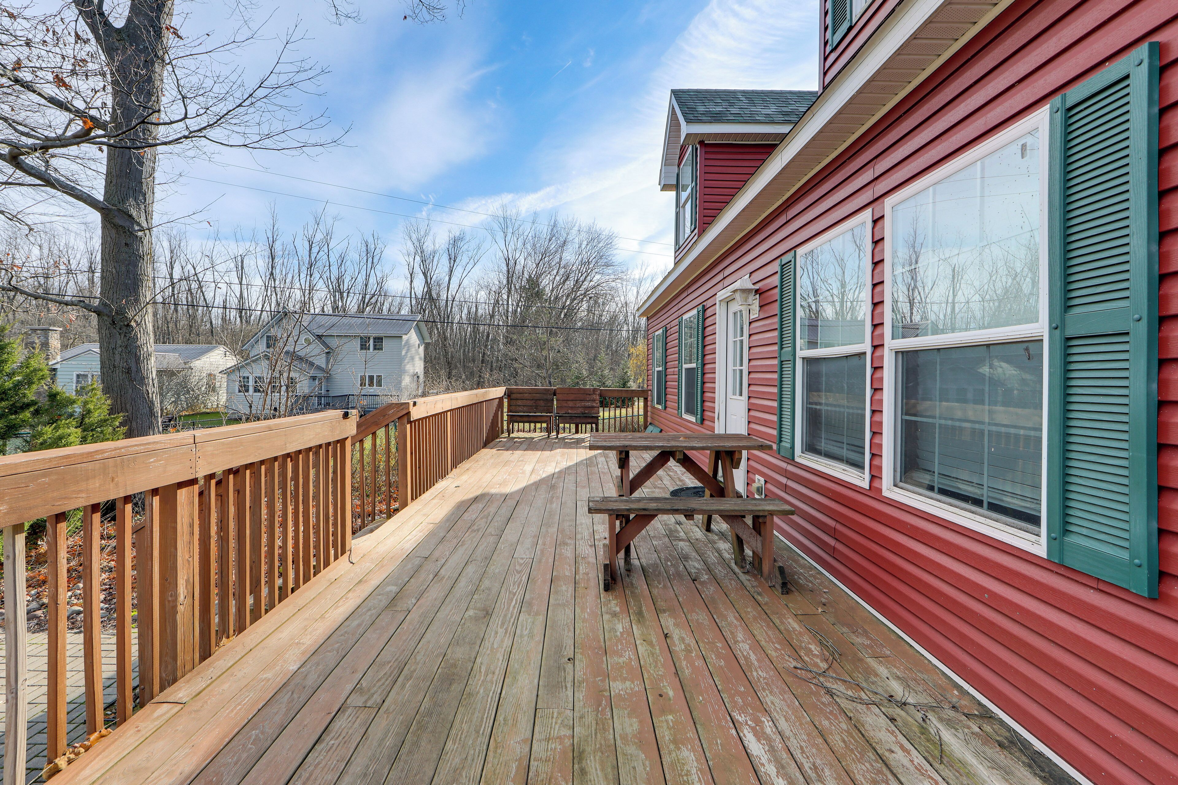 A wooden deck with a picnic table and a railing, overlooking a residential area with houses.