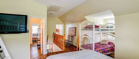 A spacious room with a large bed, a ceiling fan, a TV, and a bunk bed.